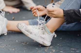 crop kid tying shoelaces on sneakers